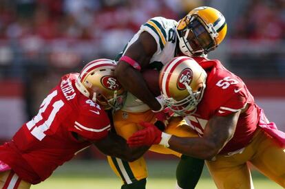 Ty Montgomery, de los Packers, resiste un ataque de Antoine Bethea y Ahmad Brooks, de San Francisco.