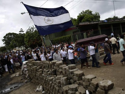 Un grupo de personas carga un féretro frente a una barricada, este jueves, en Masaya.