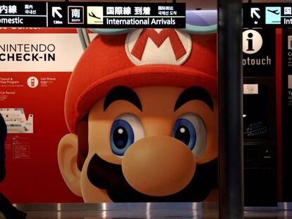 Una persona pasa junto a un cartel de Nintendo con una imagen de Super Mario.