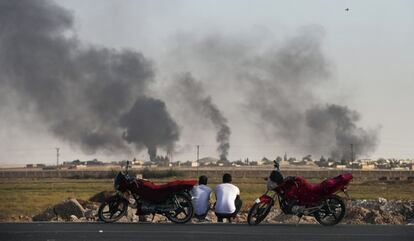 Dos personas con sus motos en el sudeste de Turquía, en la frontera con Siria, observan el humo en una localidad al norte de Siria, durante el bombardeo de las fuerzas turcas, el 10 de octubre de 2019.