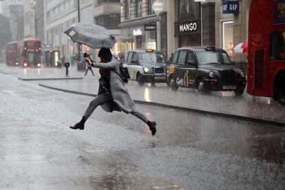 Una mujer salta un charco formado en la calle debido a las fuertes lluvias caídas en Londres (Inglaterra).