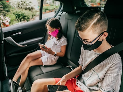 Dos niños usan sus móviles en un coche.