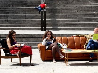 Varias personas leen en un salón de lectura al aire libre en Madrid.