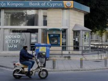 Un hombre circula ayer en motocicleta delante de una sucursal del Banco de Chipre en Nicosia (Chipre).