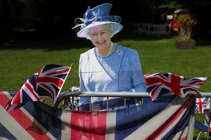 Una figura de cartón de la reina Isabel II tras una bandera de Reino Unido en una de las vallas de seguridad frente al castillo de Windsor. 
