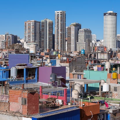 Desigualdad.
La fotografía muestra una de las villas miseria de Buenos Aires y los rascacielos de uno de los barrios más lujosos. Dos mundos separados por pocos metros. Werning, quien es economista además de fotógrafa, subraya que la inflación es un impuesto regresivo para los pobres. “A largo plazo genera pobreza y desigualdad. El rico se hace más rico porque puede comprar dólares, criptomonedas, sacar la plata afuera, aumentar los alquileres si tiene propiedades… Pero la gente pobre no tiene herramientas para protegerse y termina pagando precios más altos porque no tiene movilidad para ir a comprar a un mayorista, no le sobra plata para comprar varios productos iguales si ve un descuento ni puede pagar en cuotas con tarjeta”.
