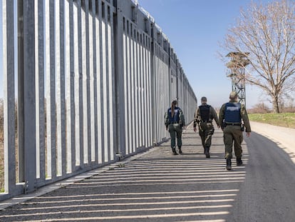 Tres agentes de frontera caminan junto a la valla de separación entre Grecia y Turquía en abril de 2023.