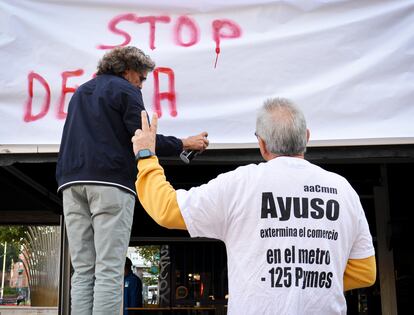 Un grupo de comerciantes escribe "Stop desahucios", minutos antes del intento de desalojo a una tienda del metro Aluche.