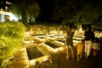 Una familia observa las tumbas iluminadas del cementerio inglés de Málaga.