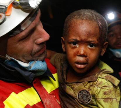 Un bombero español con un niño al que rescató de los escombros de su casa de Puerto Príncipe.