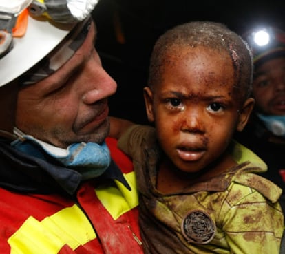 Un bombero español con un niño al que rescató de los escombros de su casa de Puerto Príncipe.