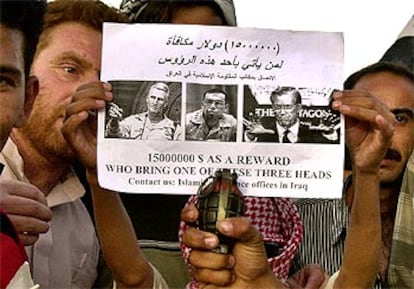 Suníes de Faluya sujetan un panfleto en el que ofrecen una supuesta recompensa de 15 millones de dinares por las cabezas de varios líderes norteamericanos.