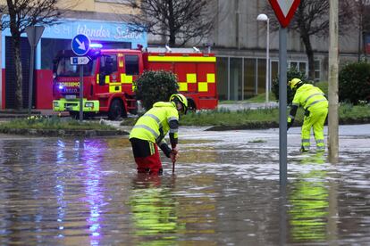 Dos bomberos trabajan en una vía inundada en Santiago de Compostela.