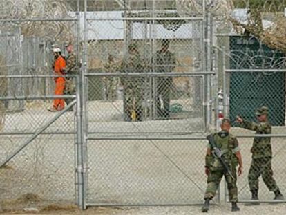 Un marino entra en el campo de Guantánamo mientras un detenido es llevado a su celda.