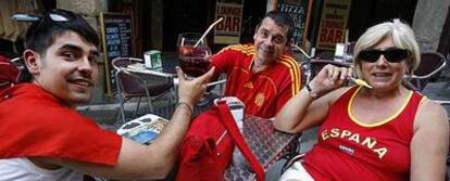 Tres aficionados toman un refresco antes del partido en la plaza Mayor.