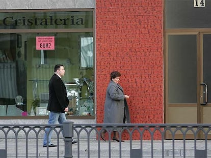 Pilar Elías, viuda de Ramón Baglietto, acompañada de un escolta, pasa por delante de la cristalería Aldako.