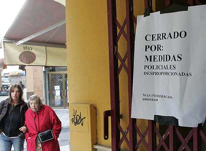 Dos vecinas de Sevilla pasan junto al Bar Serva la Bari, precintado por la Policía Local.