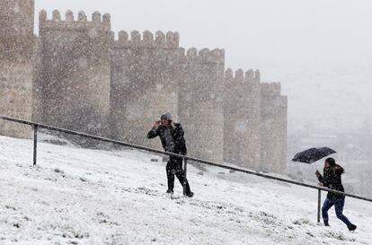 Dos personas suben hasta la muralla de Ávila bajo la nieve, el 3 de marzo de 2017. En Ávila, la AEMET ha emitido alerta amarilla, la de menor riesgo, por fuertes rachas de viento y nieve.