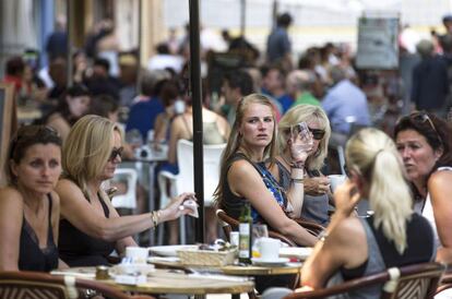 Varios turistas se refrescan en una terraza junto a La Lonja de Valencia. 