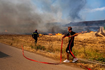 Un bombero y un voluntario intentan sofocar las llamas en un incendio forestal, en Velestino, prefectura de Magnesia, Grecia, este 27 de julio. 
