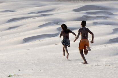 Una pareja de jóvenes corren por las dunas de arena de la playa de Atalaia, en Salinopolis, en el estado de Pará, Brasil.