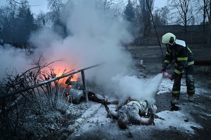 Un bombero extingue el fuego de los cuerpos de los transeúntes asesinados después de un ataque aéreo que afectó la principal torre de televisión de Kiev.