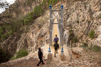 Varias personas cruzan el puente de El Saltillo, en Canillas de Aceituno (Málaga).