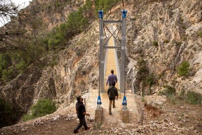 Varias personas cruzan el puente de El Saltillo, en Canillas de Aceituno (Málaga).