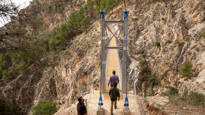 Varias personas cruzan el puente de El Saltillo, en Canillas de Aceituno (Málaga).