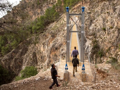 Varias personas cruzan el puente de El Saltillo, en Canillas de Aceituno (Málaga).