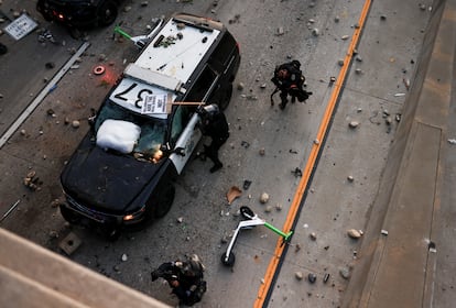 Agentes de policía junto a vehículos policiales dañados en una carretera durante las protestas de este domingo contra las redadas federales de inmigración, en el centro de Los Ángeles.