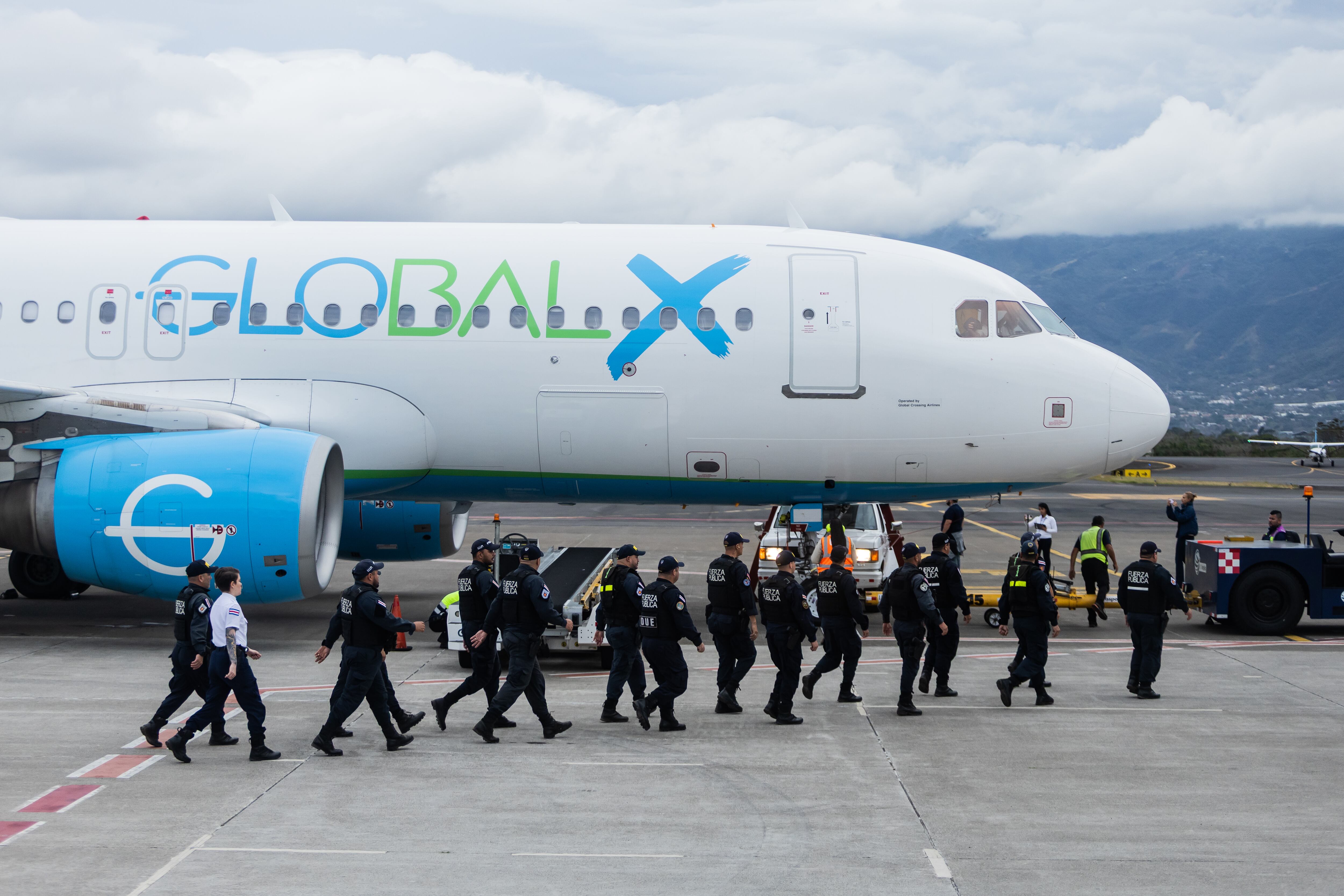 Elementos de la policía se acercan al avión para recibir a los deportados. 