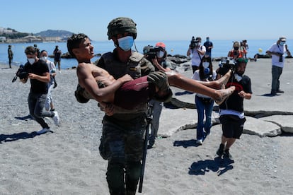 Un militar español lleva en brazos a un menor después de que haya entrado a nado en Ceuta, este miércoles.