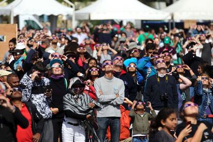 Una multitud contempla el eclipse solar anular a través de telescopios, cámaras fotográficas y gafas para eclipses, en la isla del Océano Índico de La Reunión.