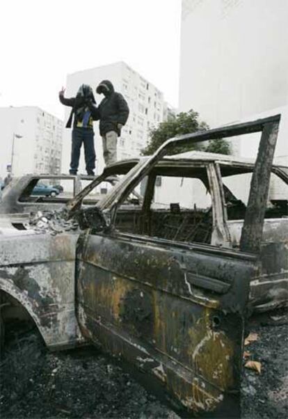 Dos jóvenes encapuchados, en el techo de uno de los automóviles quemados en Sevran, cerca de París.