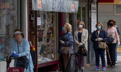 Women wearing masks wait in line to enter a store in Seville on Tuesday.