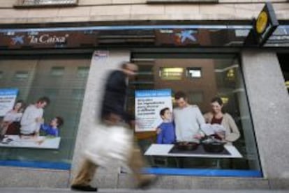 Un hombre pasa delante de una oficina de La Caixa en Madrid. 