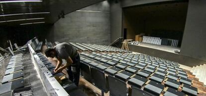 Un operario da los últimos retoques a las butacas del auditorio del centro García Lorca en Granada.