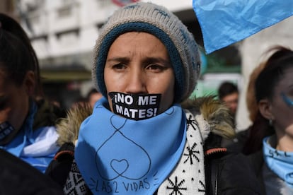 Una joven tapa su rostro con un lema contra el aborto legal. Lleva en su cuello el pañuelo celeste con la consigna "Salvemos las dos vidas", lema de la campaña.