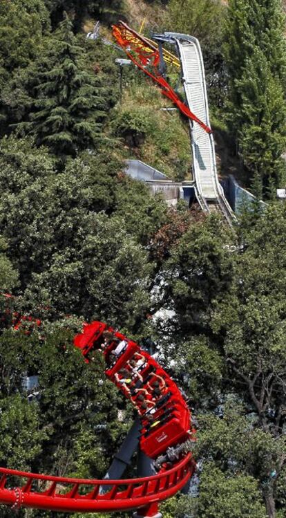 Pasajeros de la montaña rusa pasan frente a &#39;El Péndulo&#39;.