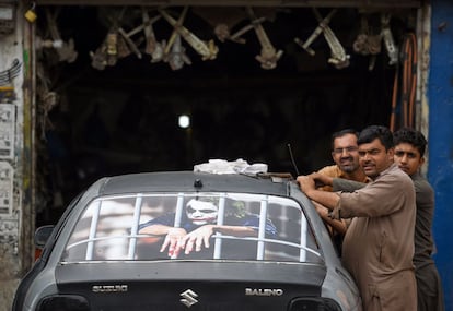 Tres trabajadores decoran un coche en un taller mecánico a las afueras de Islamabad (Pakistán). Analistas advierten que con el aumento de la población galopante de Pakistán, el país no encontrará alivio económico a corto plazo, incluso después de que el Fondo Monetario Internacional aprobó su último préstamo de 6 mil millones de dólares.