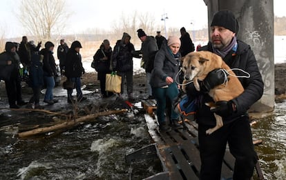 Un hombre lleva en brazos a su perro para cruzar un puente destruido en la ciudad de Irpin, el 8 de marzo. El puente fue destruido por las fuerzas ucranianas para intentar evitar que las tropas rusas entraran en la ciudad.