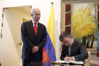 El presidente de Colombia, Juan Manuel Santos (dcha), firma el libro de visitas junto a su homólogo israelí, Simon Peres (centro izda), conversan durante una ceremonia de bienvenida en la residencia presidencial en Jerusalén (Israel).