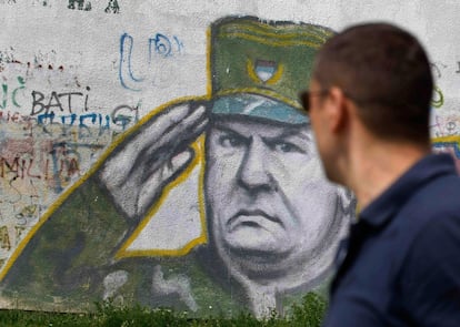 Un hombre pasea delante de un grafiti en Belgrado,  con el rostro del comandante serbio bosnio, Ratko Mladik.