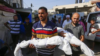 Dos hombres trasladan los cadáveres de niños palestinos hacia el hospital de los Mártires de al-Aqsa, en el municipio de Deir al-Balah, en Gaza, este viernes 12 de julio.