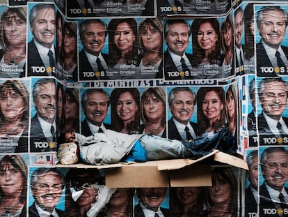 Un hombre sin hogar duerme debajo de los carteles que muestran al presidente, Alberto Fernandez, y su vice, Cristina Kirchner, el día después del triunfo del peronismo en las elecciones de 2019.