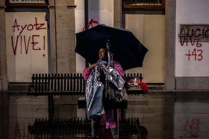 Una mujer vende impermeables y paraguas a los asistentes durante el recorrido de la marcha, este jueves en el Centro Histórico de Ciudad de México.