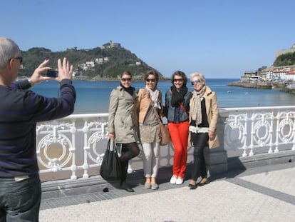 Varios turistas se sacan una foto con La Concha de fondo, en San Sebastián.