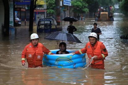 Los trabajadores de rescate recorren las calles inundadas mientras evacuan a una mujer con una piscina inflable en Pingxiang (China).