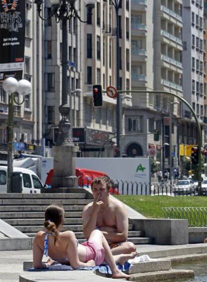 Dos turistas toman el sol ayer a las dos de la tarde en la plaza de España.